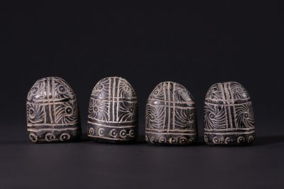 A Group of Four Black Glass Gaming Pieces with Incised White Decoration, 19th Century. A group 