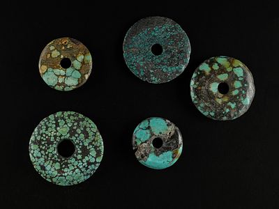A Group of Turquoise Disc Beads. A collection of five circular turquoise disc beads, each 