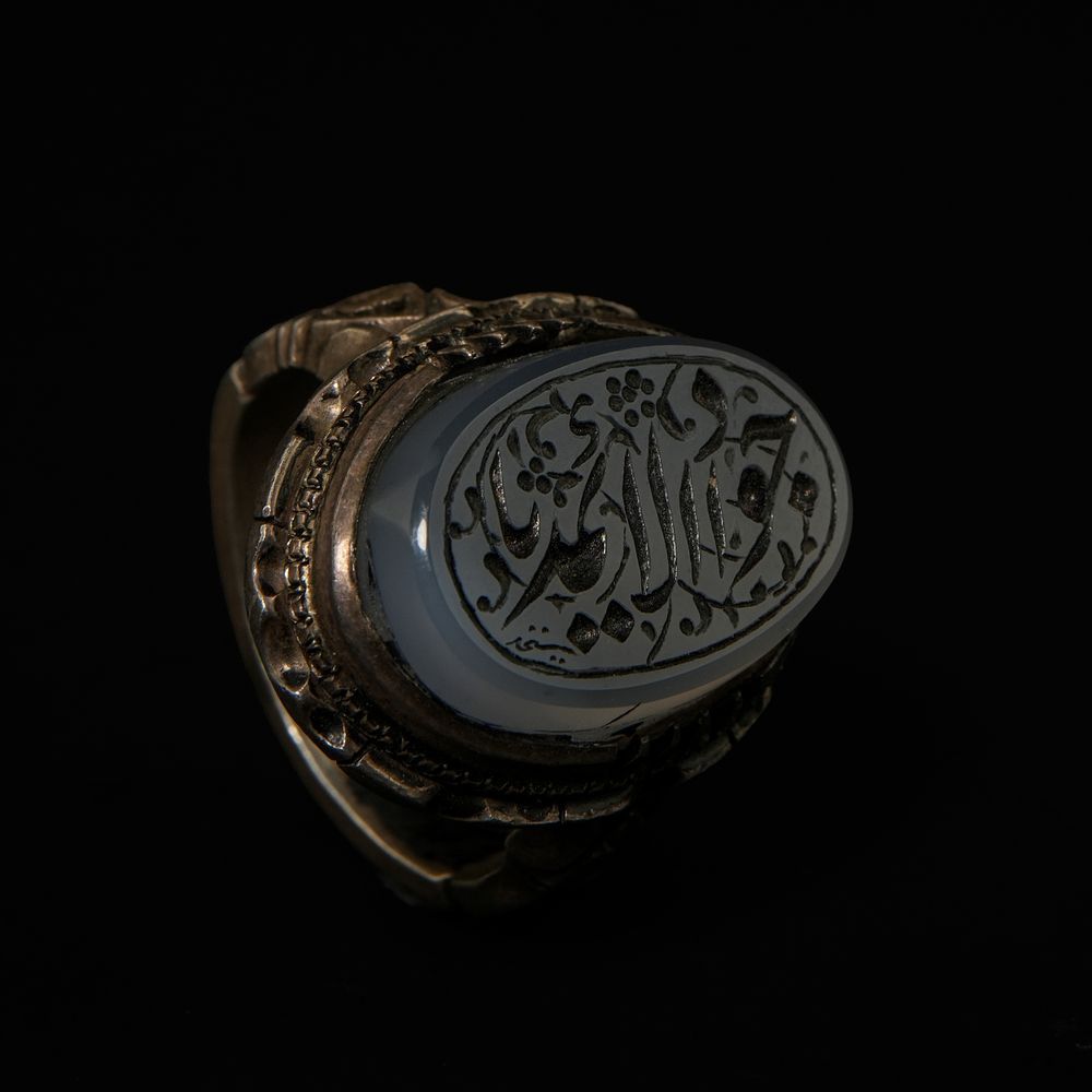 Lot 207: An Islamic Silver Ring with Carved Grey Agate...
