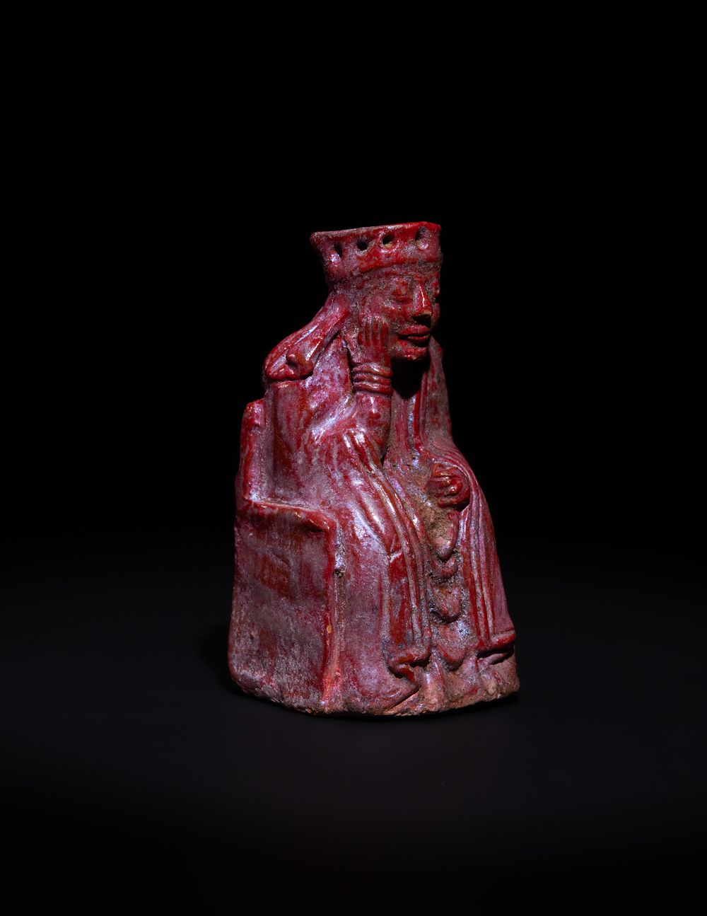 Lot 7: A RED GLAZED CERAMIC CHESS PIECE DEPICTING A SEATED KING, POSSIBLY MEDIEVAL 12TH-14TH CENTURY.