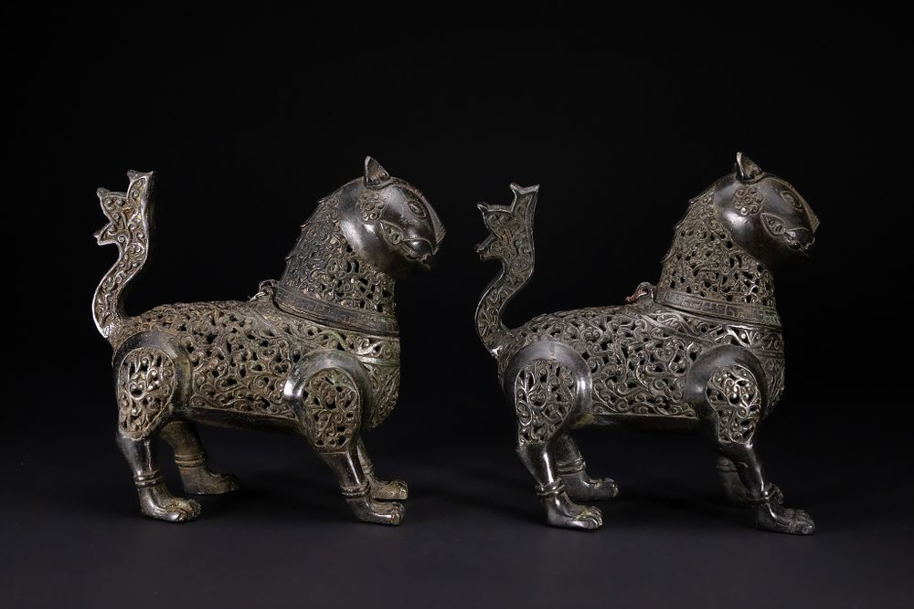 Lot 23: A PAIR OF KHORASAN CAST BRONZE OPENWORK FELINE INCENSE BURNERS.