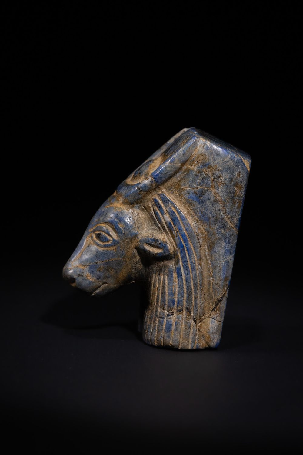 Lot 31: AN EGYPTIAN REVIVAL CARVED BLUE STONE GAMING PIECE IN THE FORM OF A BOVINE HEAD, 19TH CENTURY.