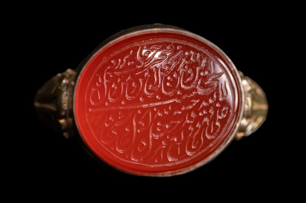 Lot 35: AN ISLAMIC SILVER SIGNET RING FEATURING A CARNELIAN INTAGLIO WITH CALLIGRAPHY.