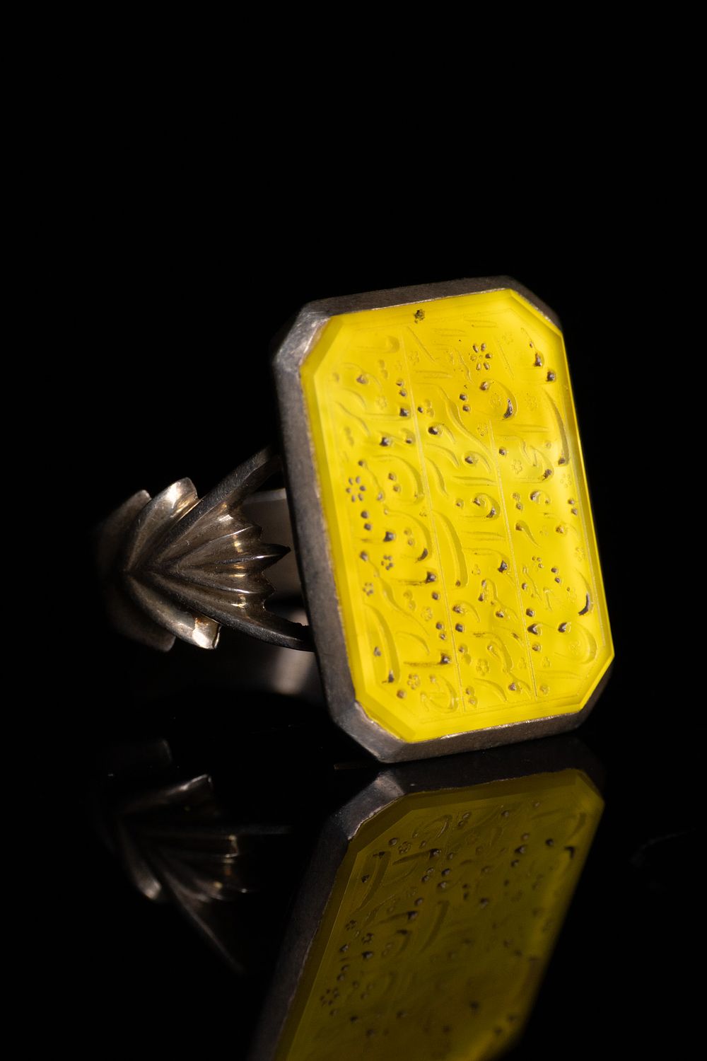 Lot 37: A PERSIAN INTAGLIO ENGRAVED YELLOW AGATE AND SILVER SIGNET RING.