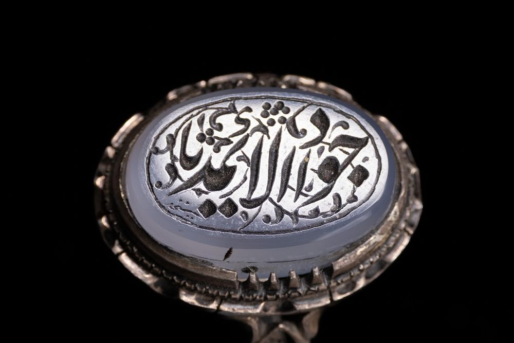 Lot 38: A PERSIAN SILVER AND ENGRAVED BLUE AGATE SEAL RING.