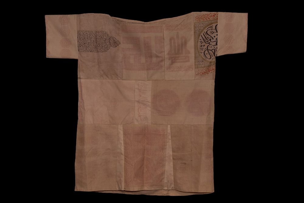 Lot 46: AN OTTOMAN TALISMANIC SHIRT JAMA WITH CALLIGRAPHIC INSCRIPTIONS AND ARCHITECTURAL RENDERINGS.