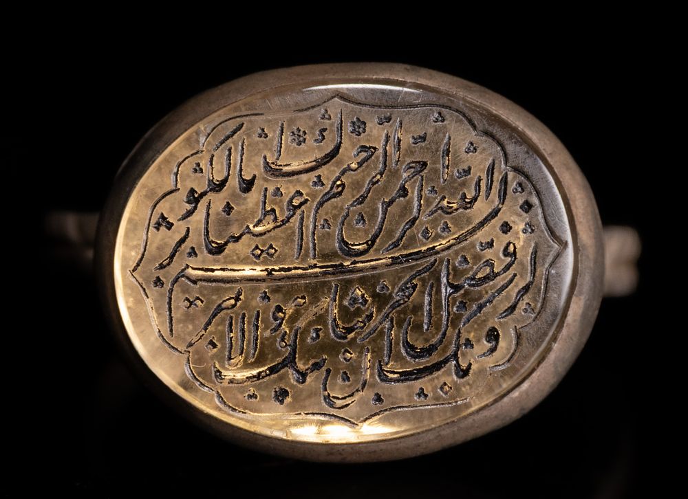 Lot 135: AN ISLAMIC SILVER AND YELLOW AGATE CALLIGRAPHIC SIGNET RING.