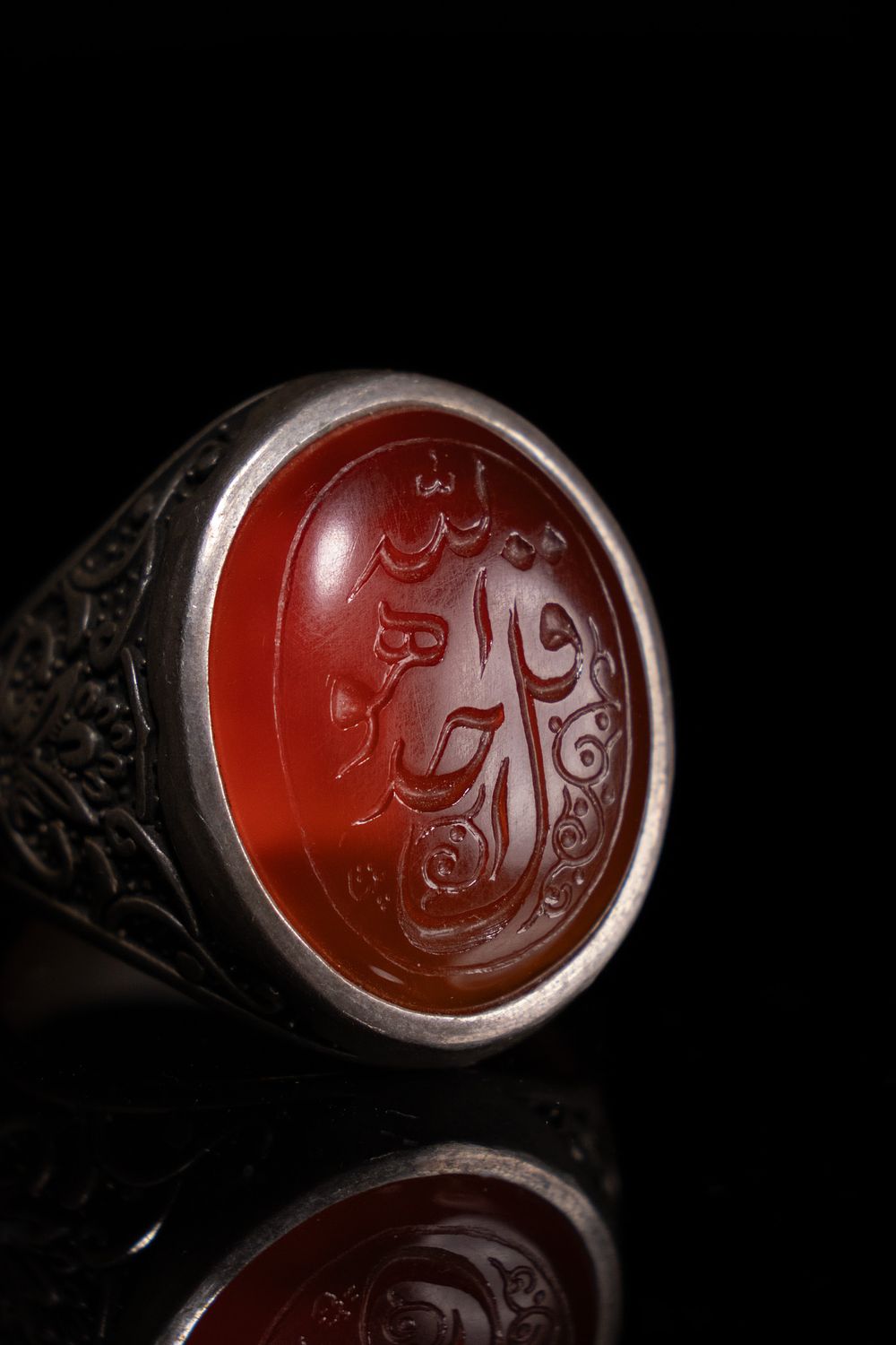 Lot 137: AN ISLAMIC CALLIGRAPHIC INSCRIBED CARNELIAN AGATE AND SILVER SIGNET RING.