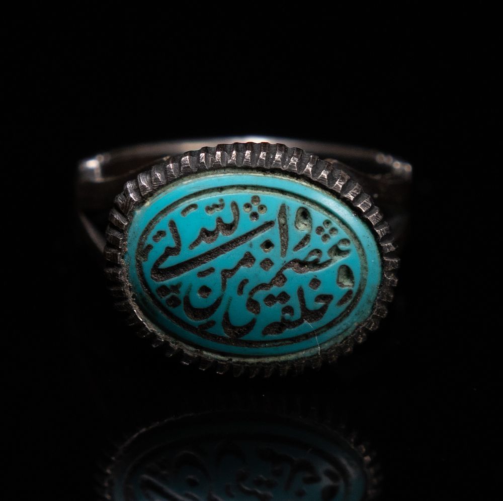 Lot 159: AN ISLAMIC SILVER SIGNET RING SET WITH AN ENGRAVED TURQUOISE CABOCHON.