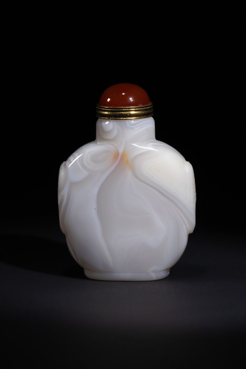 Lot 277: A CHINESE WHITE BANDED AGATE SNUFF BOTTLE CARVED WITH A BUDDHIST LION.