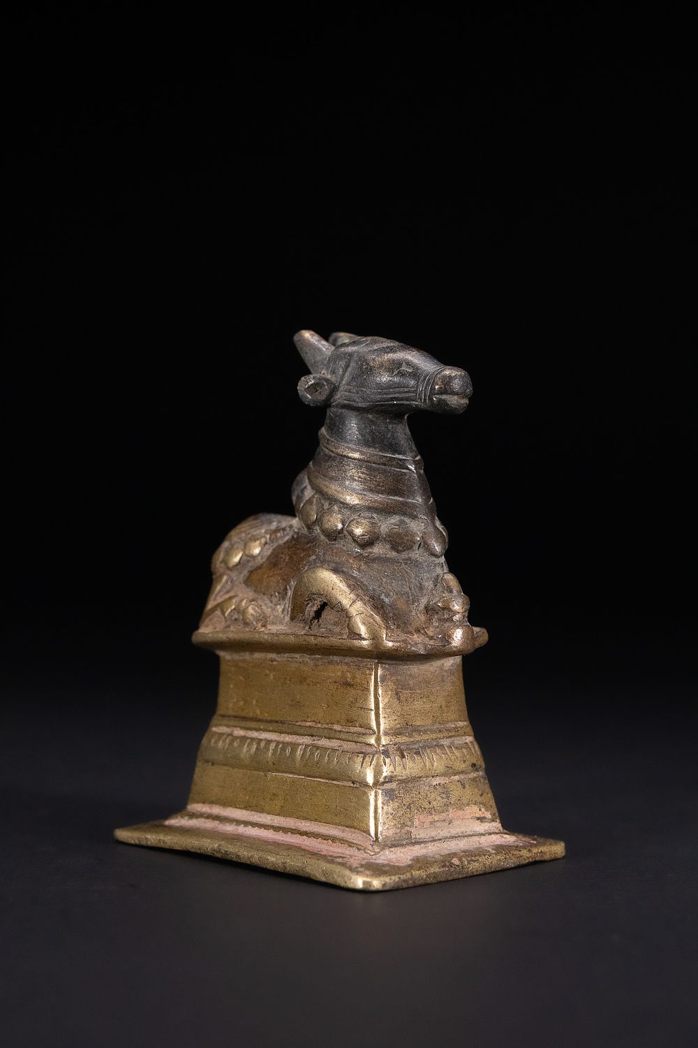 Lot 338: A SOUTHERN INDIAN OR DECCAN BRONZE VOTIVE FIGURE OF NANDI, 18TH/19TH CENTURY.