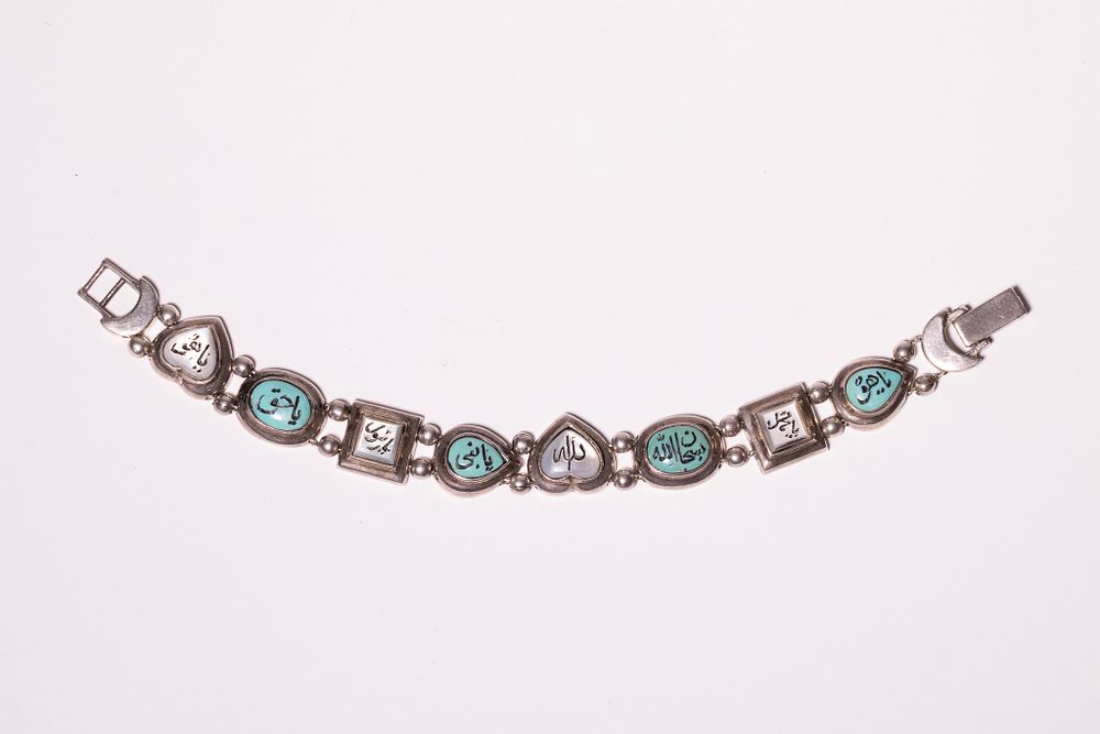 Lot 348: A MIDDLE EASTERN SILVER AND TURQUOISE INSET BRACELET WITH ARABIC INSCRIPTION.