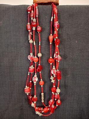 4 Strand Layered Necklace. This necklace features a vibrant mix of red, orange and metallic 