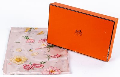 HERMÈS. A printed silk scarf with floral motif on a pale pink background 
300 - 350 €