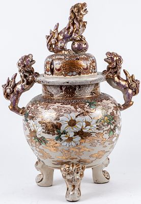 A Japanese Satsuma glazed two-handled tripod vase and cover topped by Chinese guardian lions. 