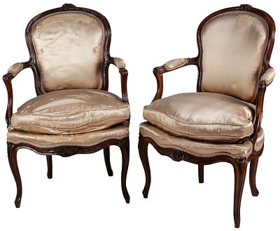 A pair of 18th-century French Louis XV carved walnut armchairs with cabriole legs and silk 
