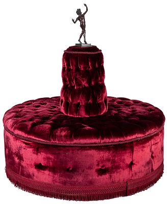 A red velvet button tufted-upholstered "Borne" sofa topped with a patinated bronze faun figure 