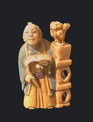 פסלון נצוקה יפני דמות נזיר. פסלון יפני מגולף בעבודת יד, מציג דמות נזיר מחייך האוחז בידו פרי. 