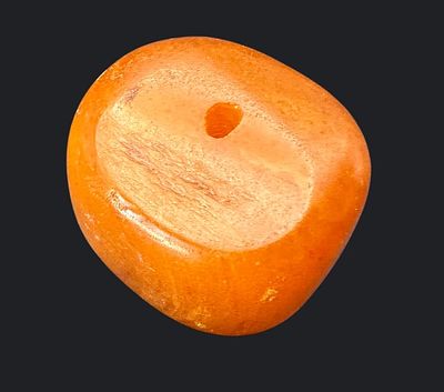 חרוז ענבר בלטי דחוס עתיק, גדול וכבד (מעל 20 גרם), בצבע כתום-דבש עם קדח מרכזי לחריזה. פריט 