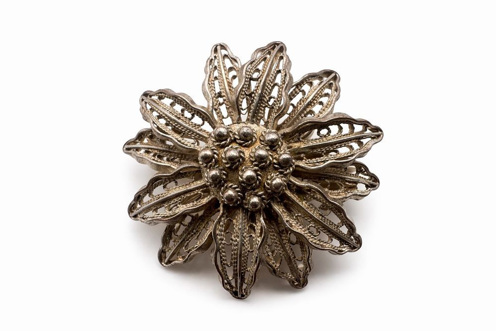 Silver filigree round brooch designed as a flower, featuring delicate coiled wire petals. 