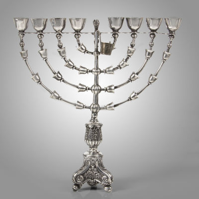 חנוכיית כסף נאה, גרמניה, המאה ה-19. חנוכייה עומדת עם עמוד מרכזי על בסיס עם שלוש רגליים. מהעמוד 