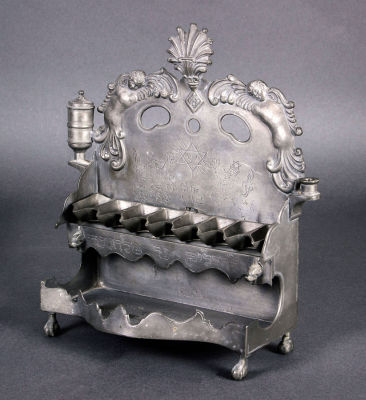 חנוכיית פיוטר, גרמניה, המאה ה-19. הלוח האחורי מורכב מכרובים בשני צידי סיומת צדף ועיטור בחקיקה של 