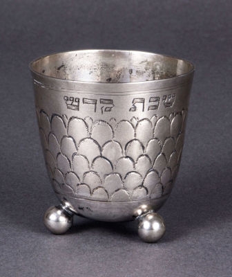 גביע קידוש מכסף, כנראה נירנברג, מחצית המאה ה-18. חרוט ומוחתם בחישוקים ומוטיב קשקשים. עם כיתוב 