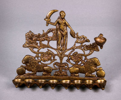 חנוכיית ברונזה נאה, איטליה, המאה ה-18/19. ברונזה יצוקה וחקוקה מעוטרת ביהודית שאוחזת בראש 