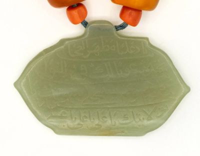 קמע איסלמי נדיר וחשוב מג'ייד ענבר וקורל, המאה ה-18. תיאור: קמע הג'ייד חרוט בכתב ערבי ומעוטר סביב 