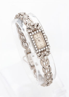 שעון אר-דקו MOVADO לאישה מזהב לבן 14 קראט ויהלומים. פני השעון המלבניים מעוטרים שוליים משובצים 