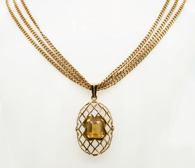 תליון זהב 14 קראט וטופז. התליון מעוצב כרשת זהב בצורה סגלגלה ומרכזו משובצת אבן טופז בחיתוך מרובע. 