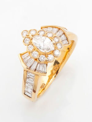 טבעת מזהב 18 קראט ויהלומים. במרכז הכתר יהלום בחיתוך טיפה (0.35 קראט בקירוב) וסביבו מסגרת 