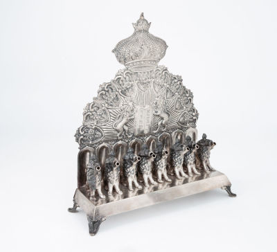 חנוכיית אריות מכסף, גרמניה, המאה ה-19. הלוח האחורי חקוק ורקוע בלוחות הברית משני צידי אריות 