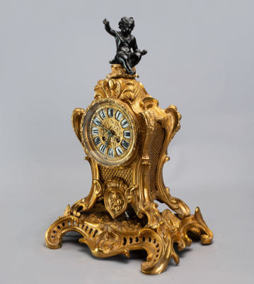 שעון אח מפואר מברונזה מוזהבת, צרפת, אמצע המאה ה-19. השעון בעל לוח עגול עם עיטורי תבליט וספרות 