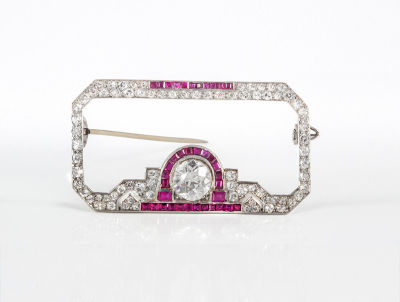 An Art Deco Diamond and Ruby Brooch. Dimensions Width: 4 cm Details Open work geometric 