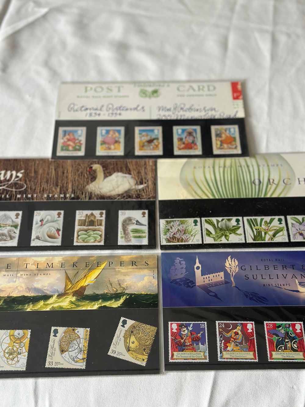 Lot 279: MIXED LOT OF MINT ROYAL MAIL STAMPS - SWANS, PICTONAL POSTCARDS, GILBERT & SULLIVAN, ORCHIDS, MARINE TIME KEERPER.