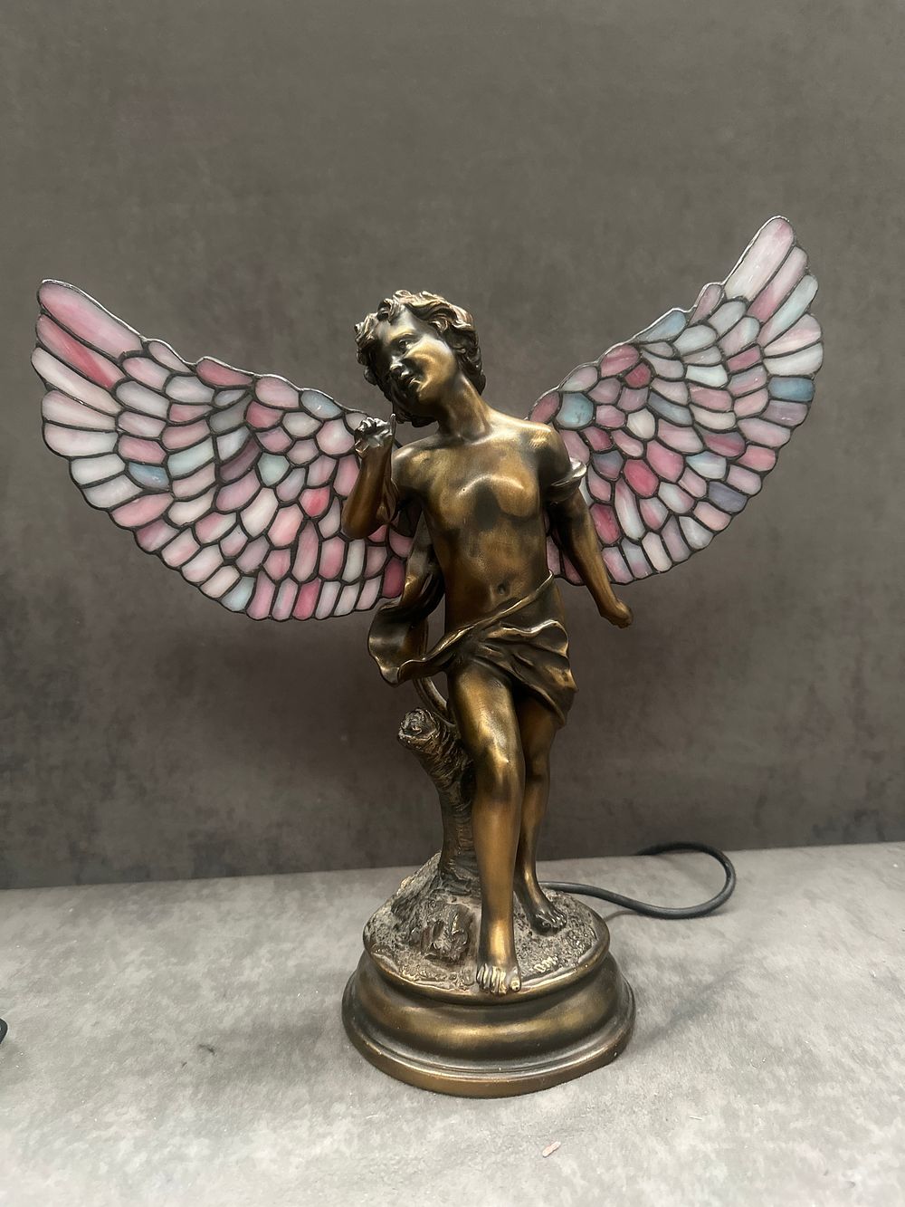 Lot 436: An Art Nouveau Style Figural Table Lamp, depicting a Winged Putto with Stained Glass Wings