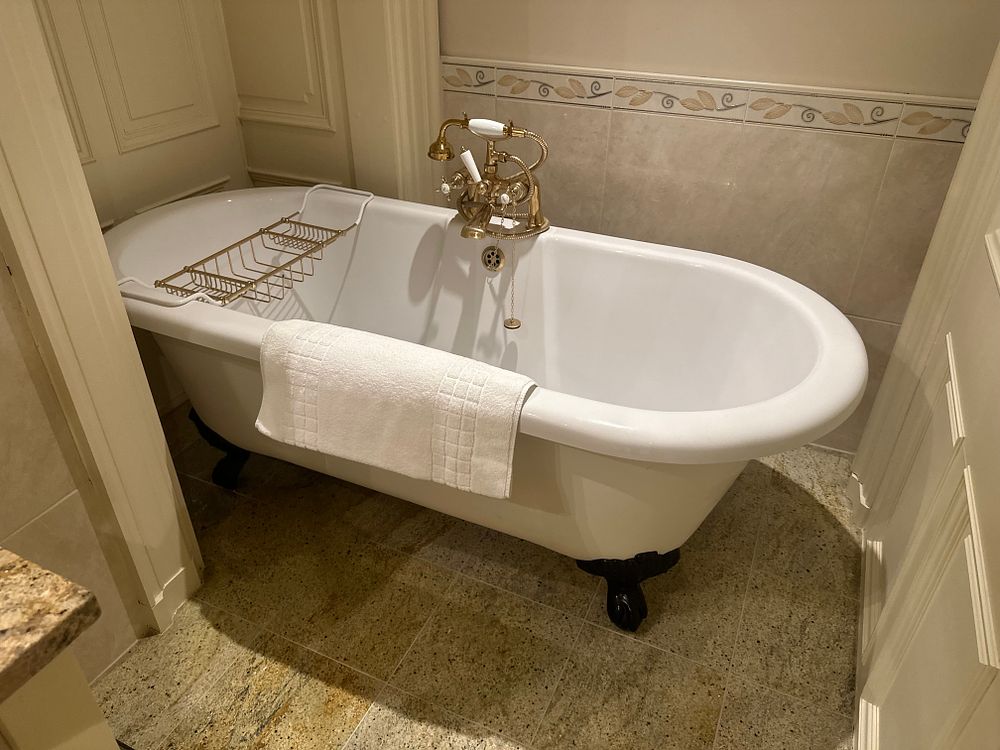 Lot 1108: A Freestanding Clawfoot Bathtub with Gold-Toned Fixtures