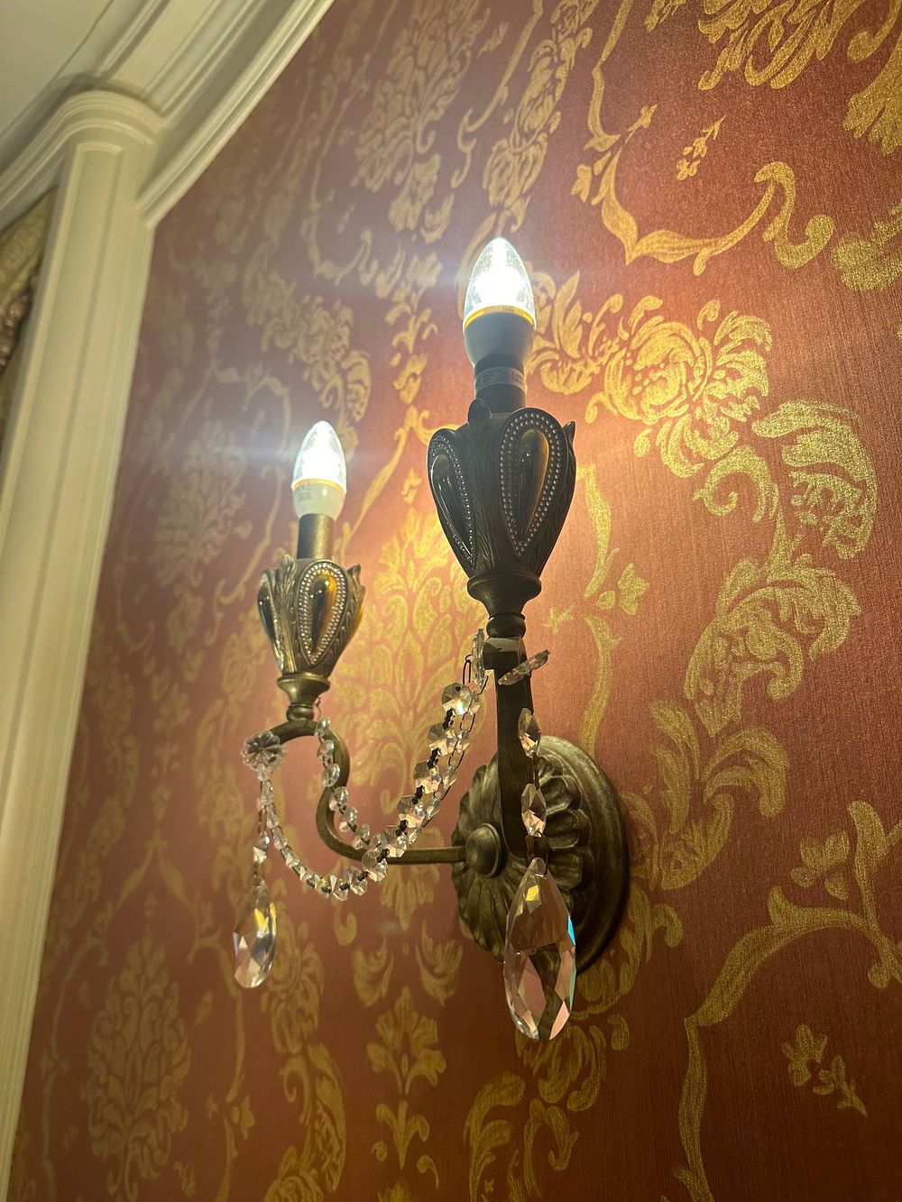 Lot 1121: A Set of Four Modern Revival Style Patinated Metal Double-Arm Wall Sconces with Crystal Pendants