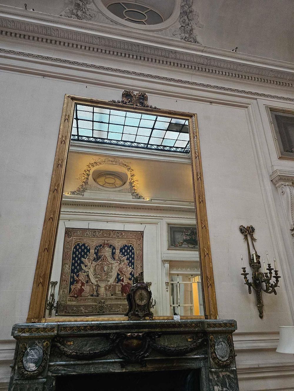 Lot 12: A French Giltwood Overmantel Mirror, Verde Antico Marble Mantelpiece, and Mantel Clock Ensemble, 18th/19th Century