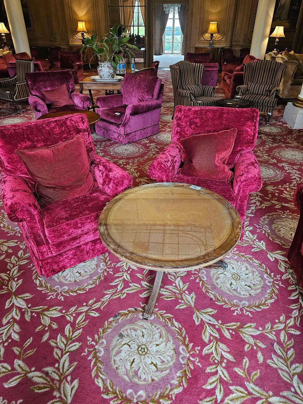 Lot 136: A Pair of Vintage Deep Red Crushed Velvet Armchairs and a Glass-Top Pedestal Coffee Table