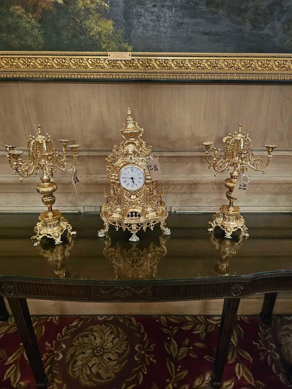 Lot 168: A French Style Rococo Revival Gilt Metal Mantel Garniture, comprising a Quartz Clock and a Pair of Five-Light Candelabra