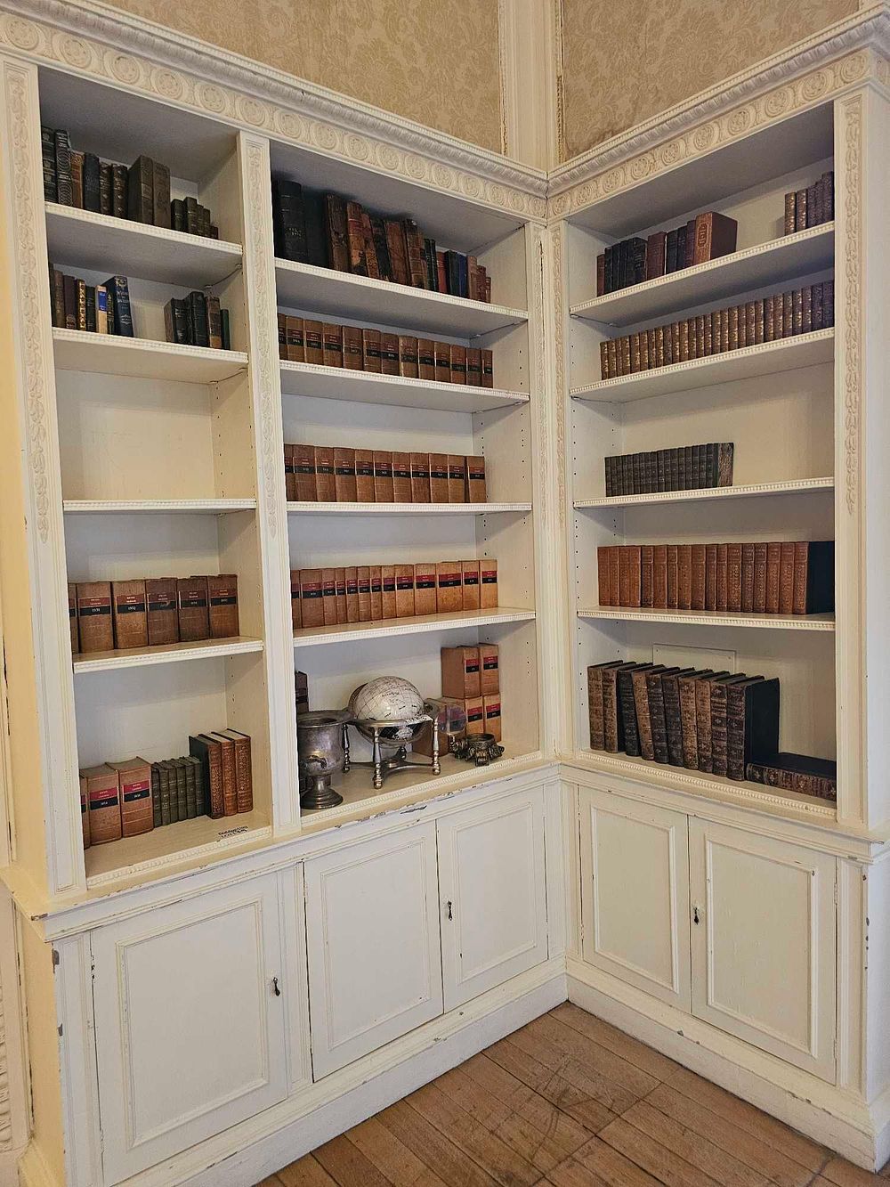 Lot 179: A Large Built-In White Painted Wooden Corner Bookshelf Unit, with a Collection of Antique and Vintage Books and Decorative Objects