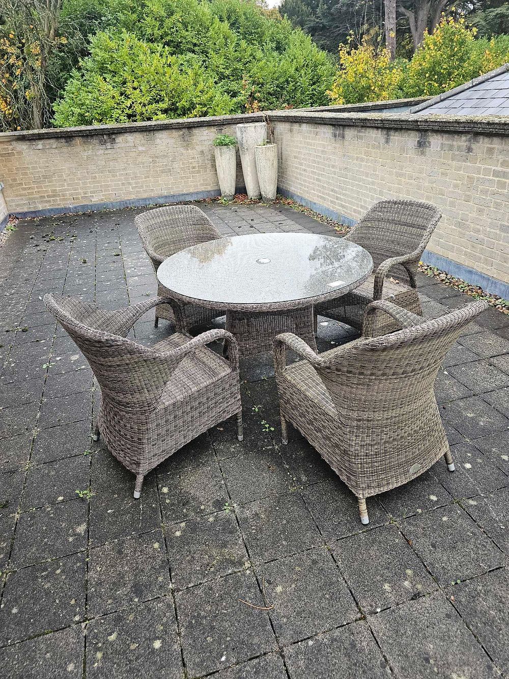 Lot 584: A Contemporary Outdoor Rattan Dining Set, comprising a Circular Glass-Top Table and Four Armchairs