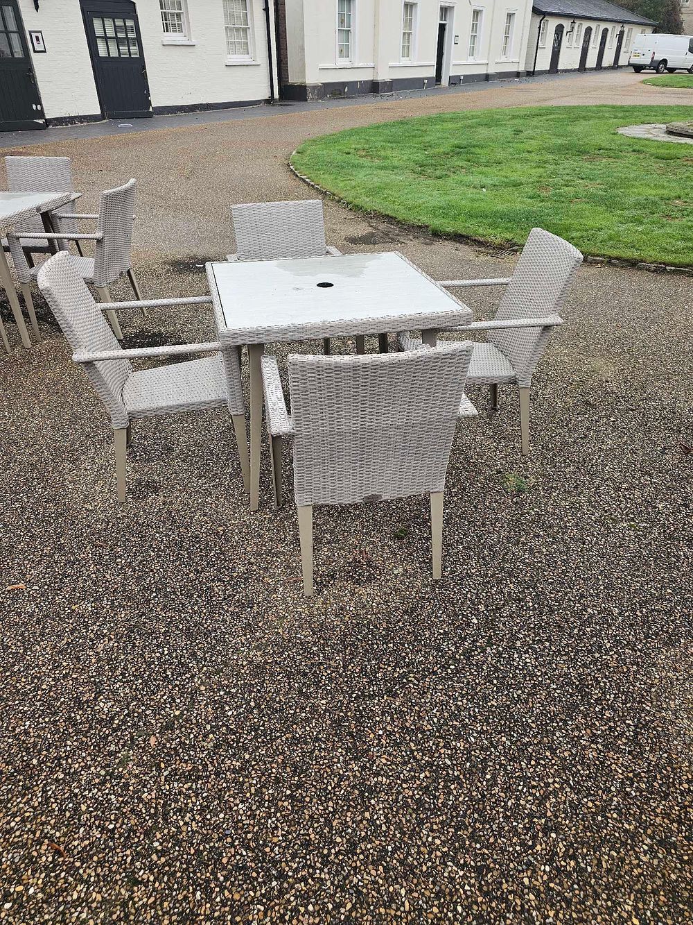 Lot 652: A Contemporary Seven-Piece Outdoor Dining Set, comprising a square glass-top table and six poly-rattan armchairs