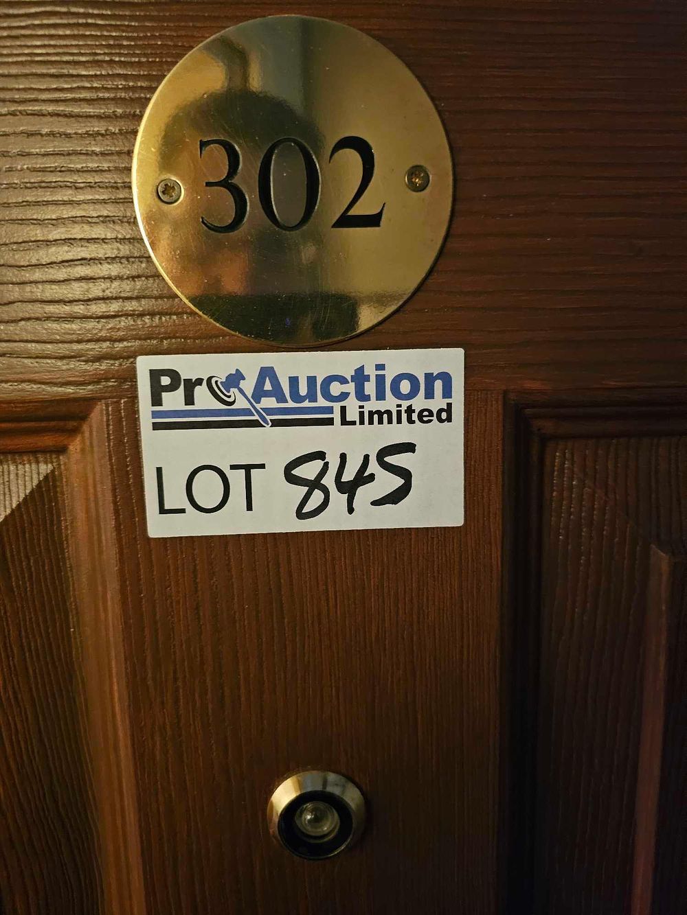 Lot 845: A Dark Brown Wooden Interior Door with Brass-Toned '302' Plaque