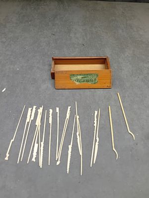 A Collection of Antique Bone Toothpicks in a Wooden Box. An open-top rectangular wooden box 