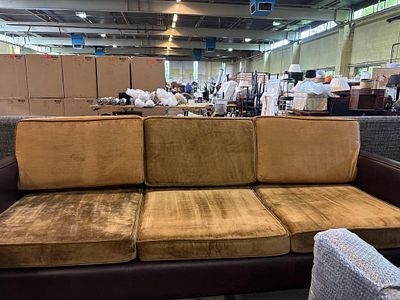 A long, low-profile sofa with a distinctive design. It features dark brown leather frame arms 