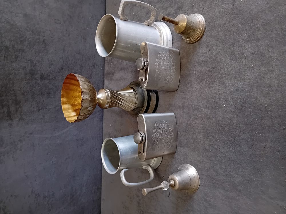 Lot 321: An Assortment of Metalware Including Tankards, Hip Flasks, Hand Bells, and a Trophy