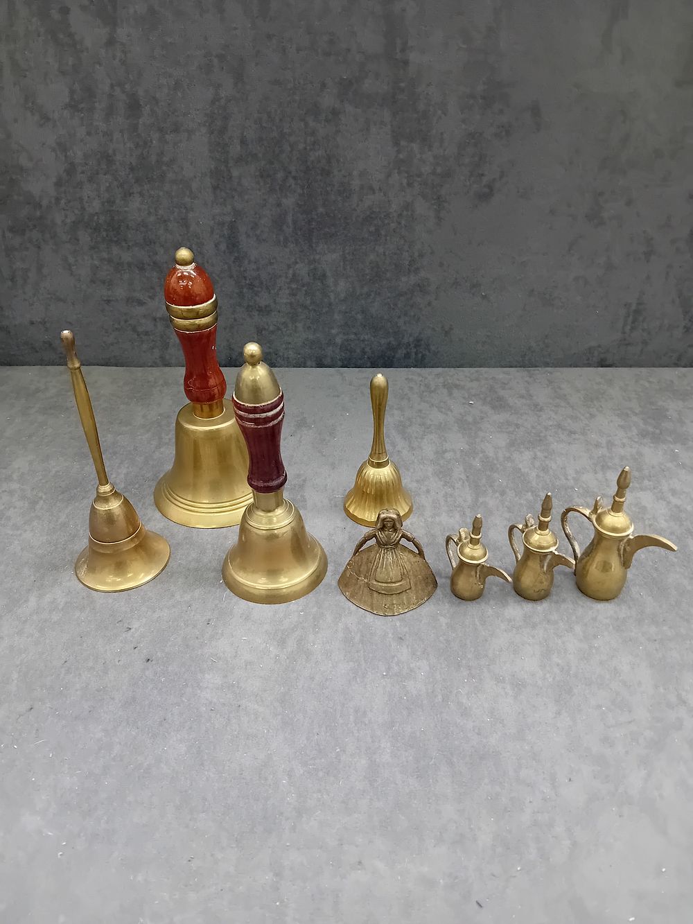 Lot 556: A Collection of Decorative Scalloped Brass Bells, Miniature Dallahs, and a Figurine